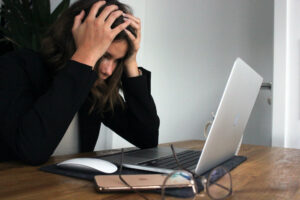 Image of a frustrated woman sitting infront of a laptio